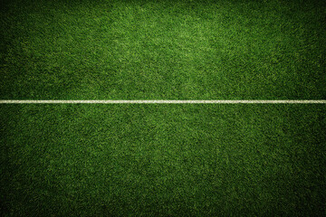 Lush green grass field with white line running across center, viewed from above, representing sports field or stadium. vibrant texture and color evoke sense of freshness and energy
