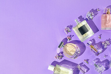 Fototapeta na wymiar Flat lay composition with perfume bottles and lilac flowers on violet background. Space for text