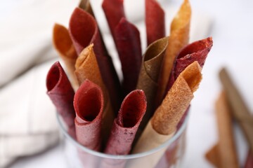 Tasty fruit leather rolls on white background, closeup