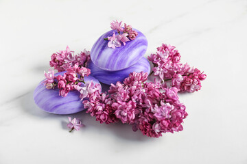 Soap bars and lilac flowers on white table, closeup