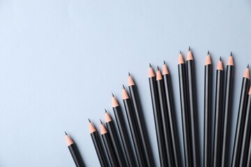 Many sharp graphite pencils on light grey background, flat lay. Space for text