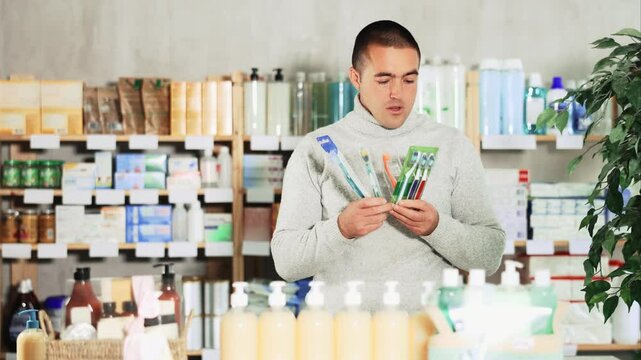 Male shopper chooses best toothbrush in supermarket. High quality 4k footage