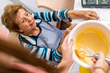 Grandmother teaching granddaughter baking skills in the kitchen