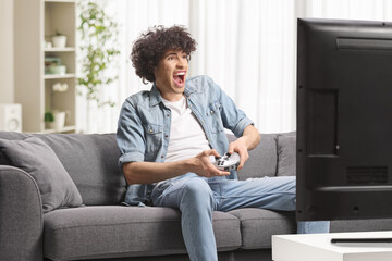 Excited guy sitting on a sofa and playing video games