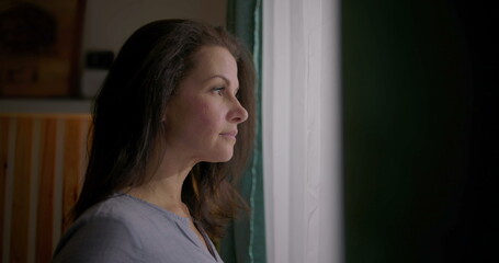 Woman gazing thoughtfully out of window, profile view, serene expression, contemplating life...