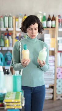 Positive middle-aged female buyer choosing convenient liquid hand soap at household goods shop 