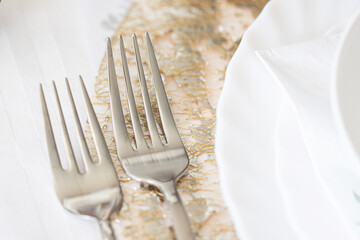 Elegant table setting with forks. Classic white porcelain plate. Fine cutlery on white tablecloth....