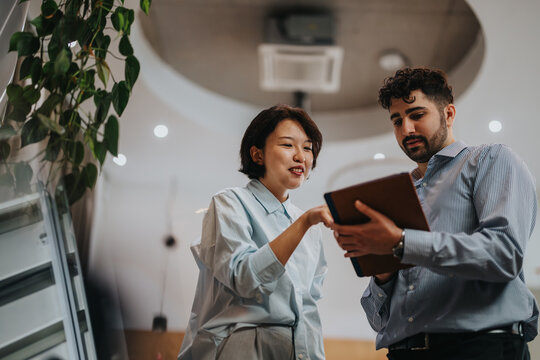Two people engage in conversation while referring to a tablet, emphasizing teamwork, technology, and collaboration in a contemporary co working office setting