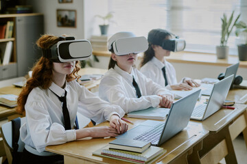 Students wearing virtual reality headsets and using laptops at classroom desk. Engaging in interactive learning experience with technology enhancing educational process