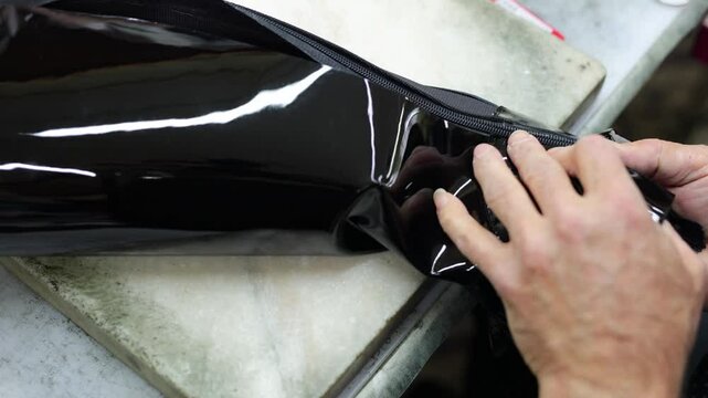 A shoemaker repairs the zipper on leather boots.