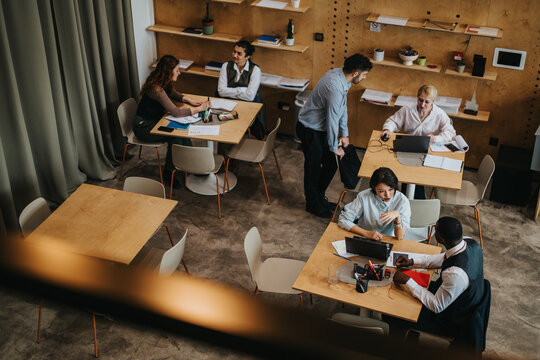 A co working area where diverse people engage in activities, fostering teamwork and productivity in a contemporary, rustic setting characterized by wood furniture and practical office decor.