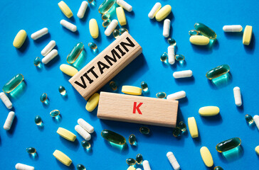 Vitamin K symbol. Concept word Vitamin K on wooden blocks. Beautiful blue background with pills....