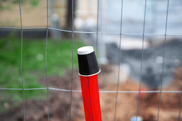 Red plastic pipe covered with a paper coffee cup for rain protection, showcasing improvised...