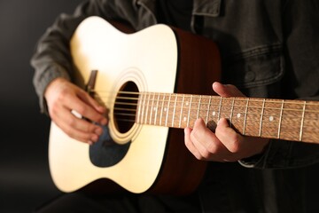 Fototapeta premium Man playing guitar on black background, closeup