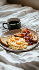 Breakfast served in bed with scrambled eggs, bacon, toast, and a cup of coffee in a cozy setting