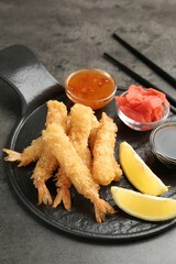 Tasty tempura shrimps, lemon, ginger and sauces on grey textured table