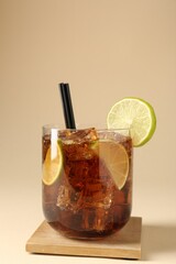 Tasty Cuba Libre cocktail in glass on beige background
