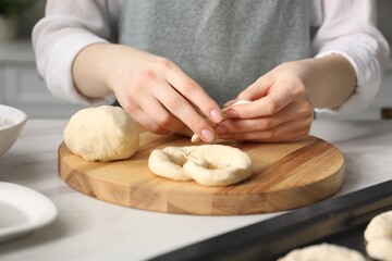 Woman shaping pretzels at table in kitchen, closeup