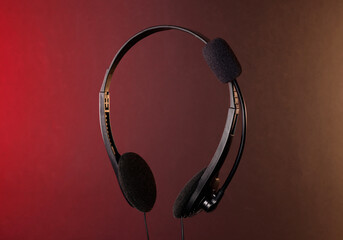 Headset with microphone in air on color background