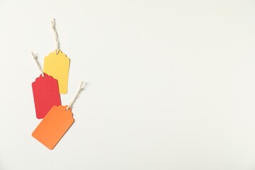 Blank tags with strings on white background, flat lay. Space for text