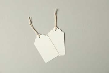 Blank tags with strings on grey background, flat lay