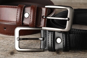 Two leather belts on wooden table, closeup