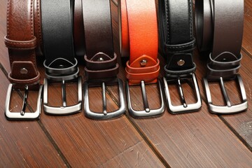 Many leather belts on wooden table, above view