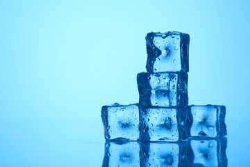 Cubes of clear ice on light blue background, closeup. Space for text