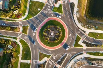 City street traffic on roundabout intersection with moving cars. View from above of urban circular...