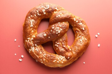 Tasty pretzel with salt on red background, top view