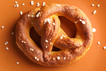 Tasty pretzels with salt on plate, top view