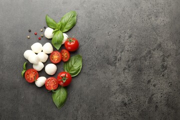 Mozzarella cheese, tomatoes, basil and peppercorns on grey table, flat lay. Space for text