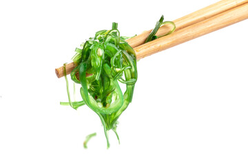 Chopsticks holding Japanese seaweed salad. Japanese cuisine - Wakame salad, Chuka seaweed salad isolated on a white background.