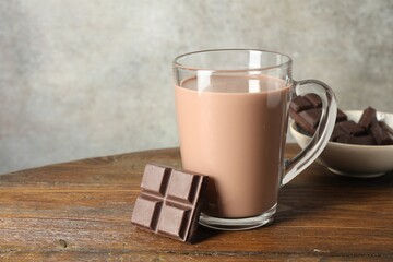 Chocolate milk in glass cup and ingredient on wooden table, space for text