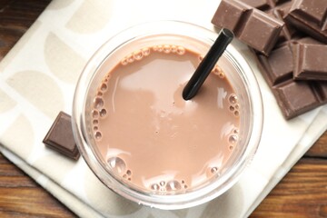 Chocolate milk in glass and ingredient on wooden table, flat lay