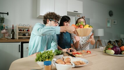Happy father move to music while cooking food and prepare lunch at modern kitchen. Active dad dancing to song while making healthy food or salad surrounded with vegetable and kitchenware. Pedagogy.