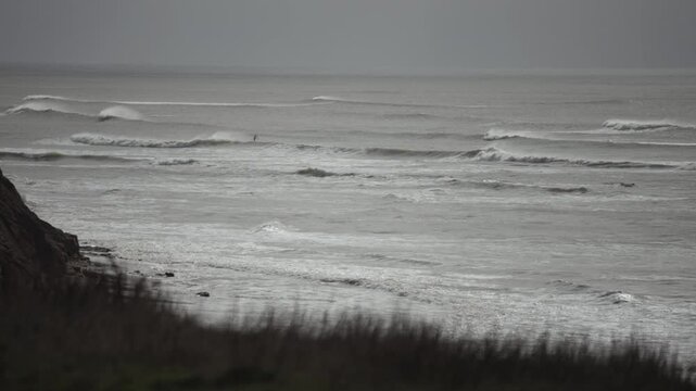 The ocean is calm and the sky is overcast. The waves are small and the