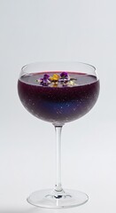 A wine glass filled with a purple liquid and flowers