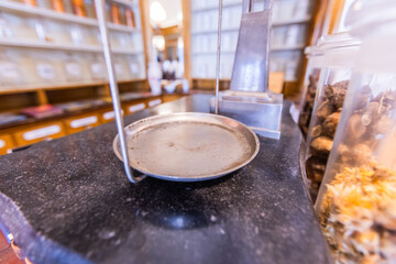 Vintage Balance Scale Pan and Apothecary Jars in Historical Pharmacy Setting