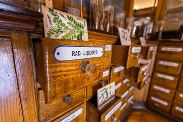 Rustic wooden drawers in an ancient apothecary or herbalist shop, with some drawers open revealing...