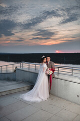 Young beautiful couple of newlywed posing in the evening against the background of an atmospheric...