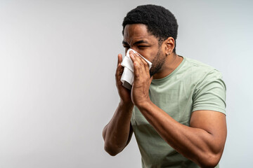 Allergic black man blowing on wipe isolated. Sick man got flu allergy sneezing in handkerchief...