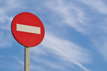 No entry traffic sign against a clear blue sky with wispy clouds during daylight