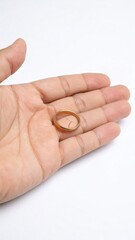 Close up shot of a gold wedding ring resting on an open palm on a white background.
