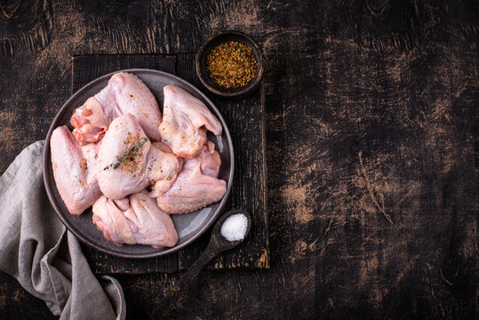 Raw chicken wings on black background.