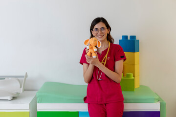 Young pediatrician holding plush toy in colorful office