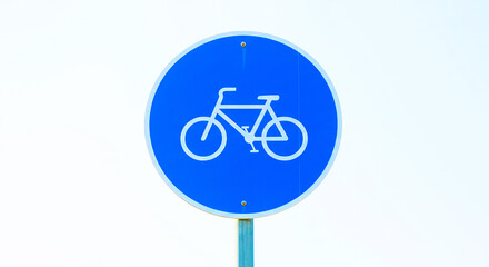 Blue round bicycle sign with white bicycle symbol against a bright white background in outdoor setting