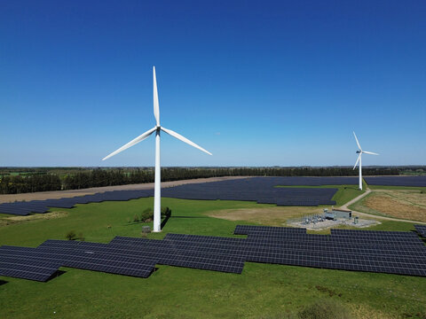 Solar panels and wind turbines in green landscape under blue sky – renewable energy