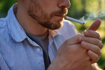 Man lighting cigarette with lighter outdoors, closeup