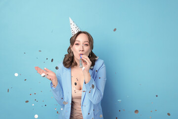 Birthday celebration. Woman with party horn and confetti on light blue background